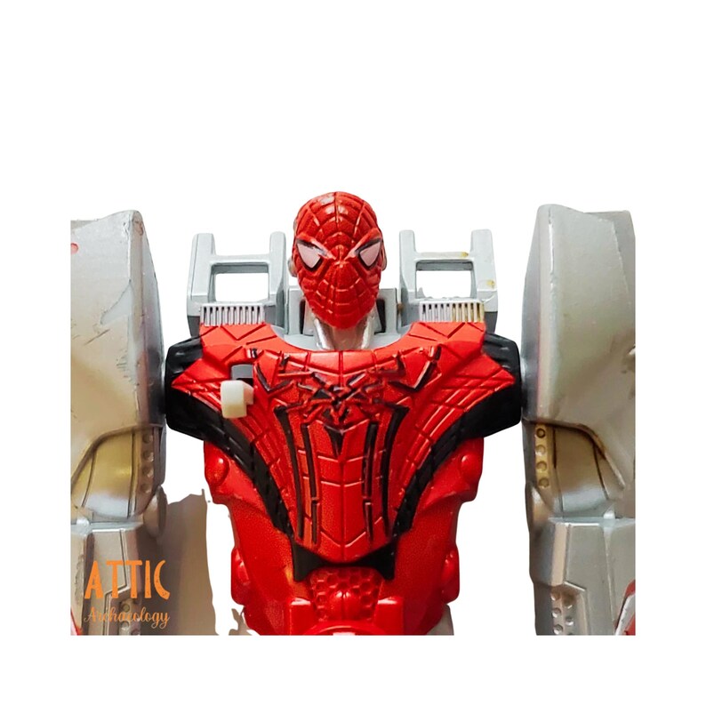 Może przedstawiać: Czerwono-srebrna figurka Spider-Mana. Figurka ma czerwoną maskę i klatkę piersiową z czarnymi detalami pajęczyny. Ramiona są srebrne, a figurka jest ustawiona pionowo.