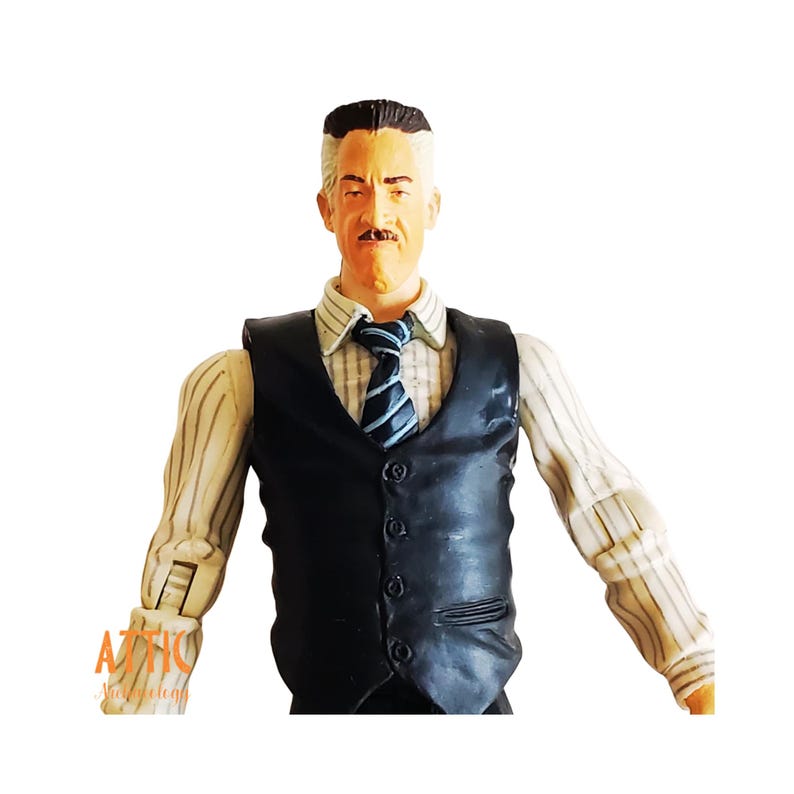May include: A detailed action figure of a man with a distinguished mustache, wearing a black vest over a striped shirt and a blue and white striped tie. The figure has a stern expression and is posed with arms slightly outstretched.
