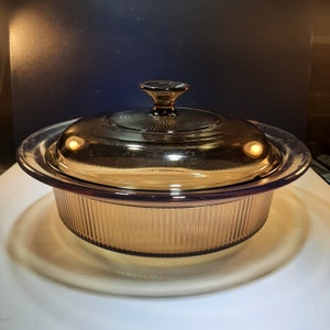 May include: A brown glass baking dish with a glass lid. The dish has a ribbed design and the lid has a knob.