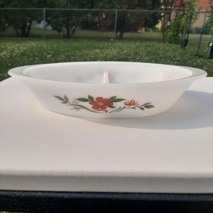 May include: White oval divided serving dish with a floral design featuring a red flower with green leaves and orange accents.