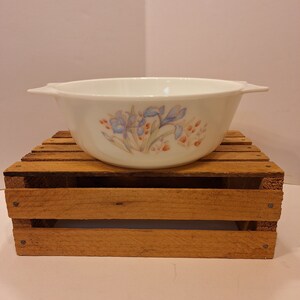 May include: White ceramic baking dish with a floral design featuring blue and pink flowers. The dish has two handles on the sides.