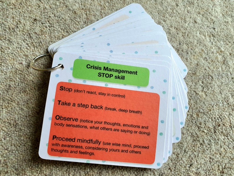 May include: A set of white cards with green and orange accents. The cards are labeled "Crisis Management STOP skill" and include the steps to take when in a crisis: Stop, Take a step back, Observe, and Proceed mindfully.