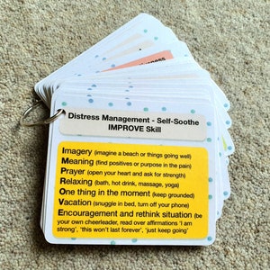 May include: A set of yellow and white cards with blue polka dots, labeled "Distress Management - Self-Soothe IMPROVE Skill". The cards list self-soothing techniques such as "Imagery", "Meaning", "Prayer", "Relaxing", "One thing in the moment", "Vacation", and "Encouragement and rethink situation".