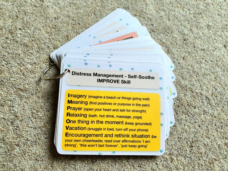 May include: A set of yellow and white cards with blue polka dots, labeled "Distress Management - Self-Soothe IMPROVE Skill". The cards list self-soothing techniques such as "Imagery", "Meaning", "Prayer", "Relaxing", "One thing in the moment", "Vacation", and "Encouragement and rethink situation".