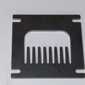 May include: A black metal plate with a rectangular cutout and a row of evenly spaced teeth along the bottom.