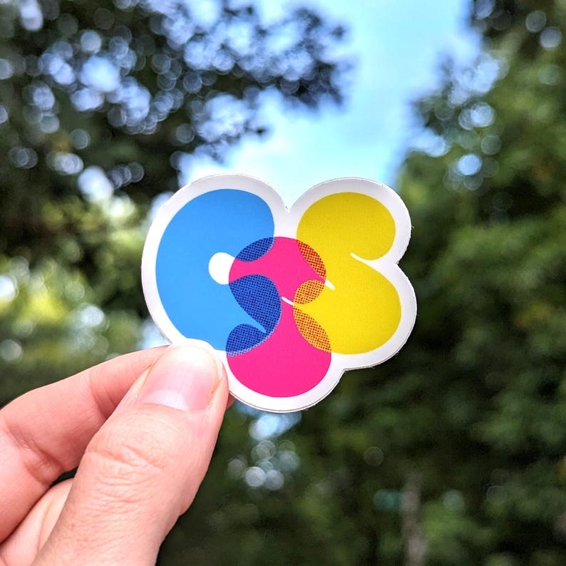 A photo of a CSS sticker in CMYK colors against a natural background