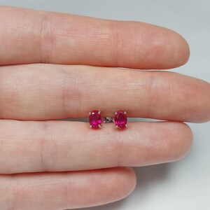 Peut inclure: Une paire de boucles d'oreilles à clous ovales rouge rubis. Les boucles d'oreilles sont serties dans un métal argenté. Les pierres précieuses sont d'un rouge vif et saturé. Les boucles d'oreilles sont présentées sur un fond clair.