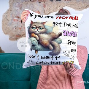 May include: White throw pillow with a grumpy cat illustration lounging on a small armchair. The pillow has text that reads "If you are normal get the hell away from me. I don't want to catch that shit."