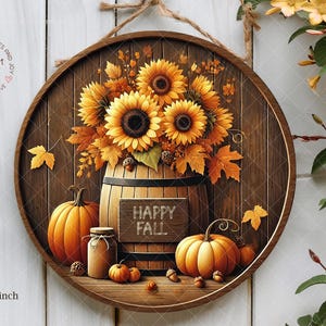 May include: A round wooden sign featuring a fall theme. The sign displays sunflowers, pumpkins, and autumn leaves arranged in a wooden barrel. The words "HAPPY FALL" are on a small sign. The sign is 12 x 12 inches.