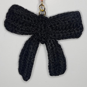 May include: A black crocheted bow with a gold metal loop at the top.