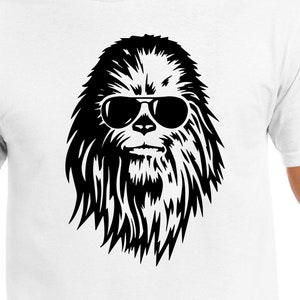 May include: White t-shirt featuring a black graphic of a furry creature wearing sunglasses. The graphic is centered on the chest of the shirt. The shirt is made of a soft material.
