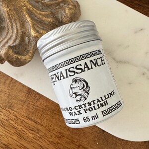 May include: A small, white jar of Renaissance Micro-Crystalline Wax Polish with a silver lid. The label features the word "RENAISSANCE" and a bulldog graphic. The jar contains 65 ml of wax polish.