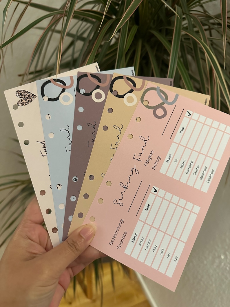 May include: A pink printable planner page with the title "Sinking Fund" and a table to track monthly savings. The table includes columns for month, rate, and amount. The page is designed with a minimalist aesthetic and features a checkmark in the rate column.