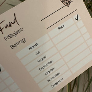 May include: A beige printable budget tracker with a leopard print heart in the top right corner. The tracker has columns for "Rate", "Month", "Due Date", and "Amount". The months listed are July through December.