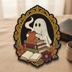 May include: An embroidered patch featuring a white ghost holding a steaming orange mug, sitting behind a stack of three books and an open book. The scene is framed by a gold ornate border with orange and dark red flowers at the bottom.