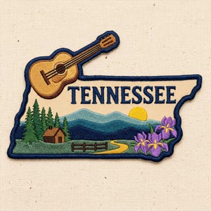 May include: An embroidered patch shaped like the state of Tennessee featuring a tan background with a dark blue border. It depicts a brown acoustic guitar, a small cabin, green pine trees, blue mountains, a yellow sun, a path, and purple irises.