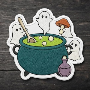 May include: An embroidered patch featuring a dark teal cauldron filled with bright green liquid, a wooden spoon, and three white ghosts. One ghost holds a brown mushroom, and a small purple potion bottle sits in front of the cauldron.