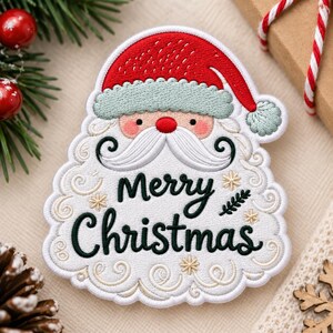 May include: An embroidered patch shaped like a Santa Claus face with a red hat, a light green brim, and a white beard. The text Merry Christmas is stitched in dark green cursive across the beard, surrounded by small gold embroidered snowflakes.