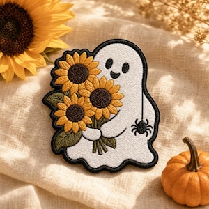 May include: An embroidered patch featuring a white ghost with a black outline, holding a bouquet of three yellow sunflowers with dark brown centers and green leaves. A small black spider hangs from a thin line attached to the ghost's hand.