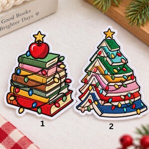 May include: Two embroidered patches featuring stacks of books arranged in a triangular shape. The first patch shows a stack of books topped with a red apple and a yellow star. The second patch shows books arranged as a Christmas tree with a yellow star.