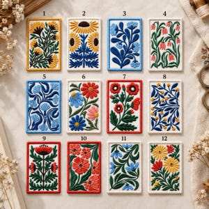 May include: A collection of twelve rectangular embroidered patches arranged in a grid, each featuring distinct floral designs with vibrant colours like yellow, blue, red, and green, numbered one through twelve with clear borders.