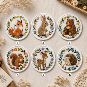 May include: Six circular embroidered patches featuring woodland animals: a fox, rabbit, bear with honey, squirrel, deer, and hedgehog. Each animal is centered within a colorful floral wreath. The patches are numbered one through six.