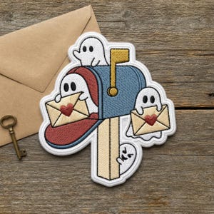 May include: An embroidered patch featuring a blue mailbox on a tan post with four white ghosts. One ghost sits on top, one is inside the mailbox, one floats to the right, and one peeks from behind the post. Two ghosts hold tan envelopes with red hearts.