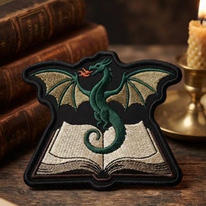 May include: An embroidered patch featuring a green dragon with tan wings breathing orange fire while perched atop an open book. The design is set against a black background with a thick black border, creating a distinct shape for the fabric applique.