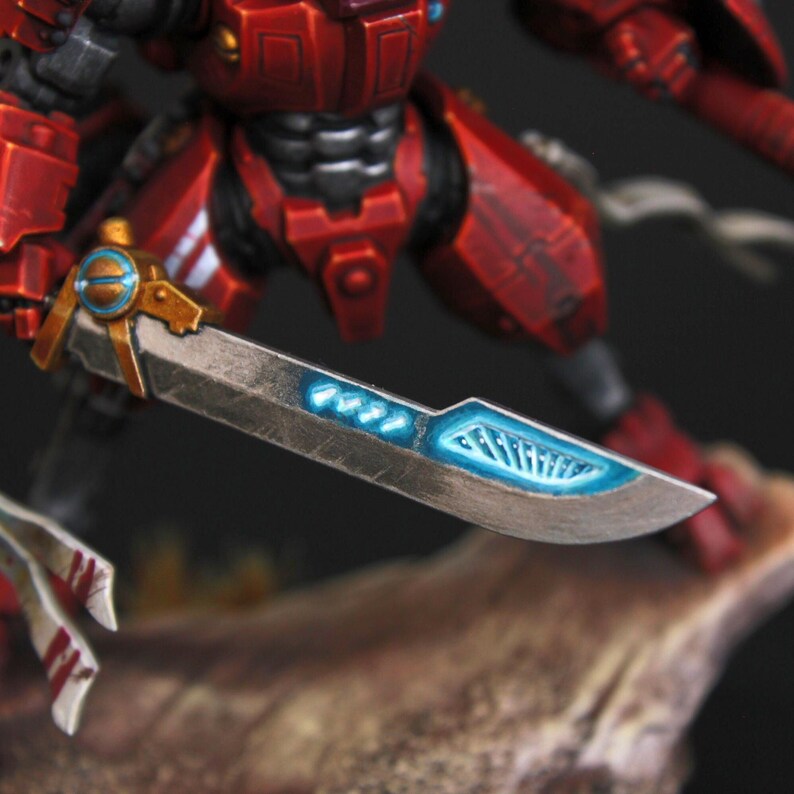 Commander Farsight Warhammer 40k miniature, professionally hand painted in Farsight Enclaves red and white. T'au Empire battlesuit commander, Elite tier display-quality commission painting, fully built, based and varnished. close up of the dawn blade with blue OSL glow