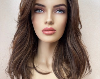 Puede incluir: Una peluca larga y ondulada de color marrón con reflejos sutiles. La peluca está peinada con un estilo informal y desenfadado, con ondas sueltas y capas.