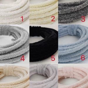 May include: Nine spools of fuzzy yarn in various colours, including white, cream, grey, black, light blue, beige, light grey, and pink. Each spool is labelled with a number from 1 to 9.