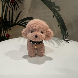 May include: A plush toy poodle with a brown fur coat and a black studded collar with a gold bell charm.