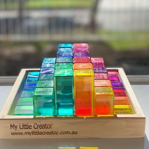 May include: A rainbow stack of clear acrylic blocks in a wooden tray. The blocks are arranged in a pyramid shape. The tray has the text "My Little Creator www.mylittlecreator.com.au" engraved on the front.