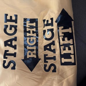 May include: A yellow fabric bag with black text and arrows. The text reads "Stage Right" and "Stage Left".