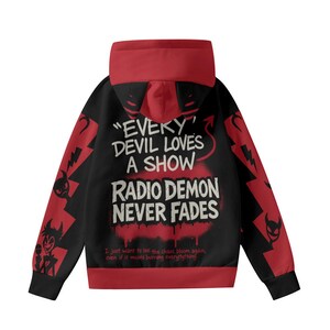May include: Black hoodie with red accents and the text "EVERY DEVIL LOVES A SHOW RADIO DEMON NEVER FADES". The hoodie features a red hood and sleeves with lightning bolt and devil graphics. The text "I just want to see the chaos bloom again, even if it means burning everything" is also included.