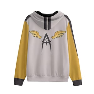 Puede incluir: Una sudadera con capucha con cuerpo blanco, mangas amarillo mostaza y detalles en negro. La parte trasera presenta una letra "A" negra estilizada con alas doradas y una franja negra en el centro de la capucha.