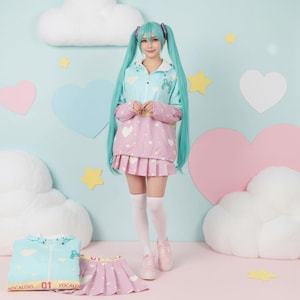 Könnte beinhalten: Ein hellblaues und rosa Cosplay-Outfit mit passendem Faltenrock. Die Jacke hat ein Wolken- und Hasen-Design, und der Rock zeigt Herzmuster. Das Outfit wird mit weißen Kniestrümpfen und rosa Turnschuhen kombiniert. Der Text "VOCALOID 01 VOCALO" ist sichtbar.