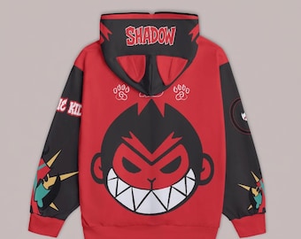 Può includere: Felpa con cappuccio rossa con cappuccio e maniche nere. La parte posteriore presenta un grande volto di scimmia dei cartoni animati con denti aguzzi e la scritta "SHADOW" sul cappuccio. Le maniche hanno disegni grafici e la scritta "IC KIL".
