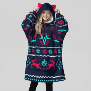 Puede incluir: Sudadera con capucha azul marino de gran tamaño con un estampado festivo de copos de nieve, renos y formas geométricas rojas y turquesas. La sudadera con capucha tiene una capucha con orejas de gato rojas y un forro de sherpa blanco.