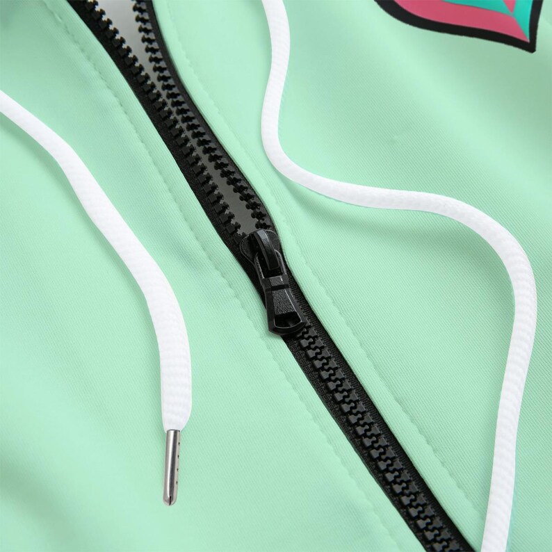 May include: Close-up of a mint green jacket with a black zipper and white drawstrings. The zipper is centered, and the drawstrings are on either side of the zipper. The jacket appears to be made of a smooth, lightweight material.