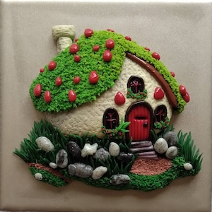 May include: A whimsical, white, mushroom-shaped house with a red door and green moss roof. The house is surrounded by small, gray stones and green grass.
