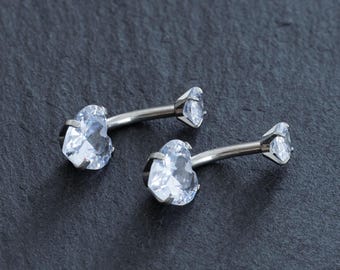 May include: Two silver belly button rings with clear heart-shaped gems.