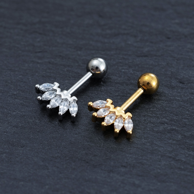 May include: Two body jewellery pieces in silver and gold with clear crystal accents. The jewellery is in the shape of a crown with a small ball on the end.