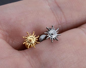 May include: Two sun-shaped earrings. One earring is gold-colored, and the other is silver-colored. The earrings have a post backing.