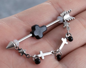 May include: A silver barbell with a black cross charm and a dangling chain with black beads and cross charms. The barbell has a pointed end and an arrowhead on the other end.
