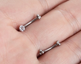 May include: Two silver curved barbell body jewelry pieces with a clear crystal gem on one end and three small silver balls on the other end.