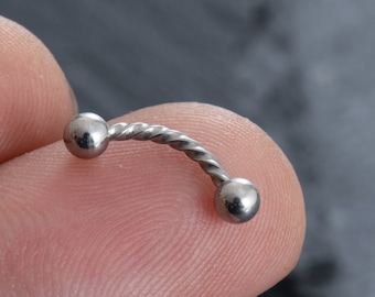 May include: A silver twisted barbell piercing with two round balls on each end.