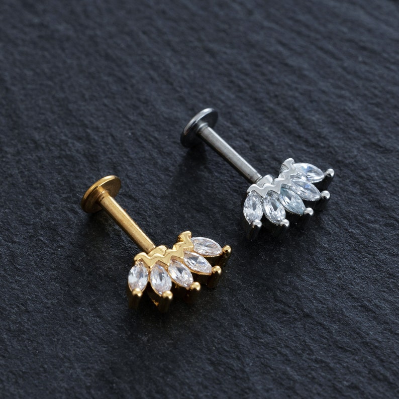 May include: Two gold and silver body jewellery pieces with clear marquise-shaped stones. The jewellery is in the shape of a crown.