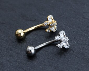 May include: Two belly button rings with clear crystal embellishments. One ring is gold and the other is silver.