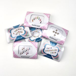 May include: Six packs of colourful, jewel-toned, adhesive, temporary, body decorations. Each pack is labelled "Kohinoor" and features a different design of gems.